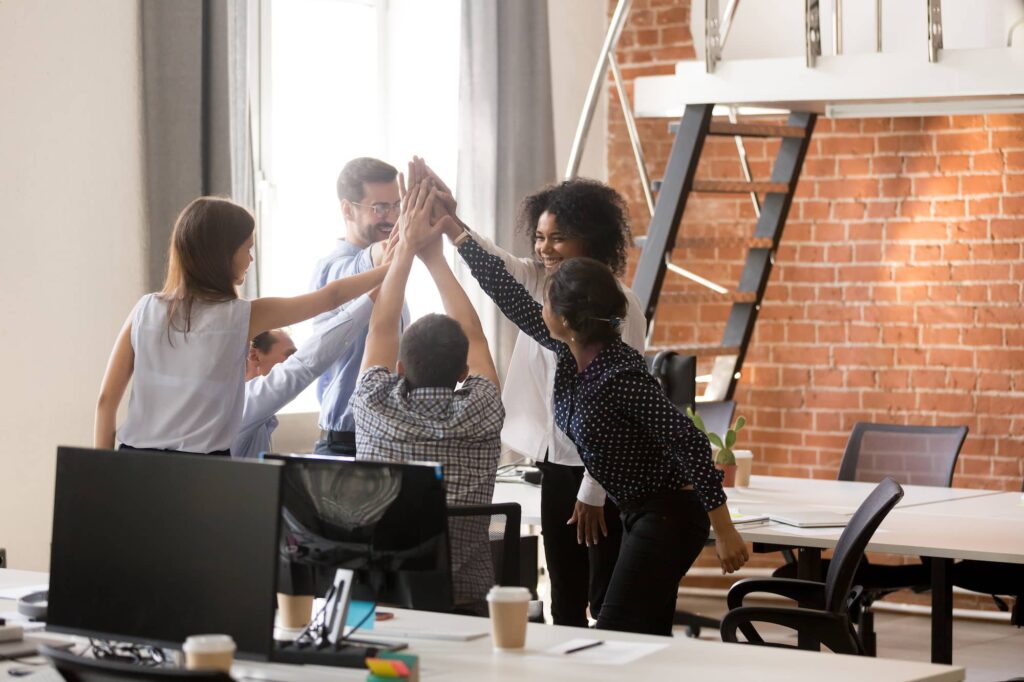 Happy motivated diverse office team giving high five together.