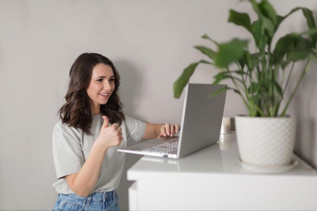 Woman giving a thumbs-up while attending a virtual onboarding event.